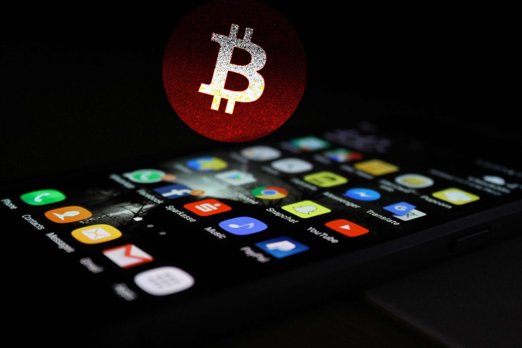 Celular com apps e símbolo do bitcoin no fundo